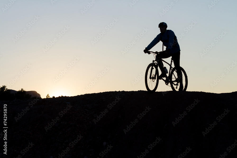 Silhouette of a cyclist with sunset on the top of a hill Silhouette of a cyclist with sunset on the top of a hill