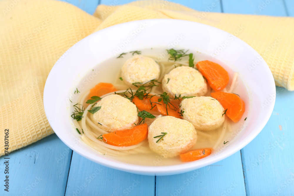 Soup with meatballs and noodles in bowl on wooden background