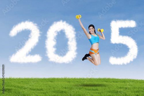 Hispanic woman with dumbbells in meadow