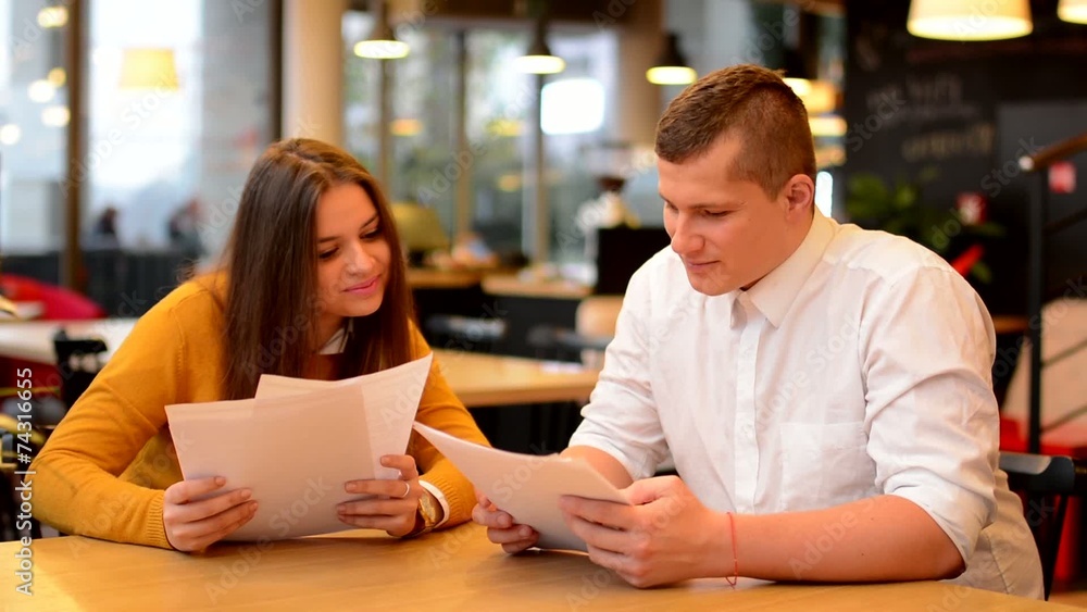 happy couple talk in cafe - couple read papers (contract) happy couple talk in cafe - couple read papers (contract)