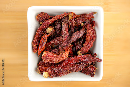 Aerial view of red kashmiri chili in white bowl on wooden plate