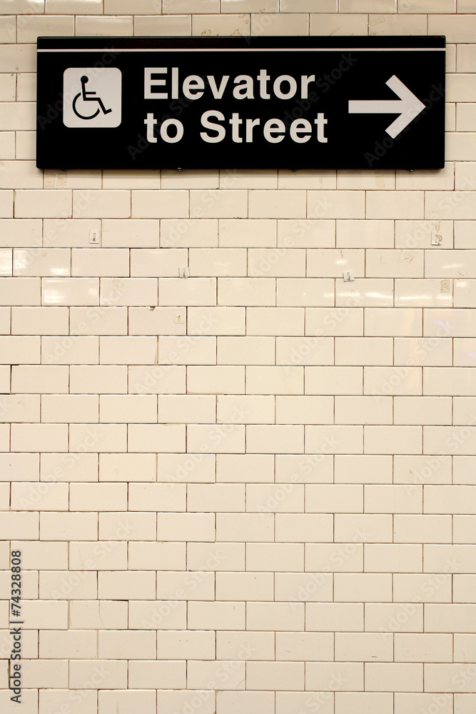 Fototapeta premium New York City Station subway directional sign on tile wall.