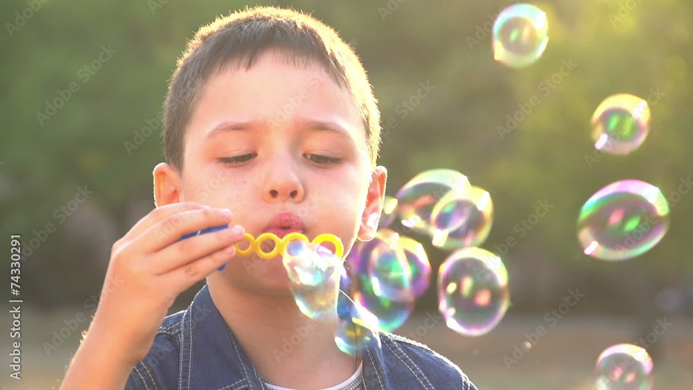 beautiful caucasian boy playing with soap bubbles in the park 1 beautiful caucasian boy playing with soap bubbles in the park 1