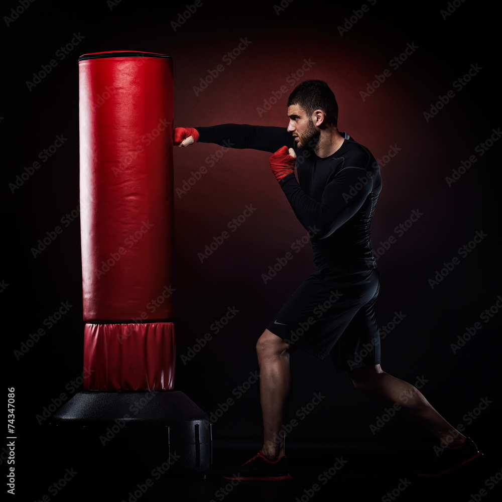 young man exercising bag boxing in studio