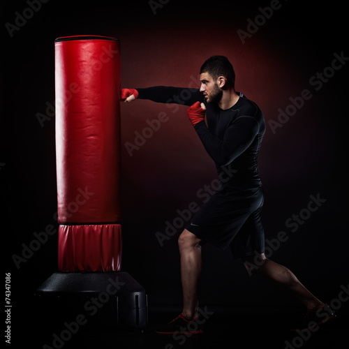 young man exercising bag boxing in studio photo