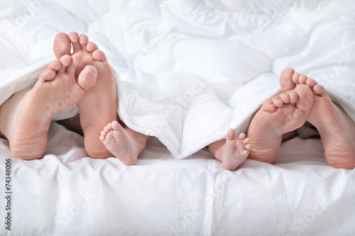 Funny family feet under the white blanket photo