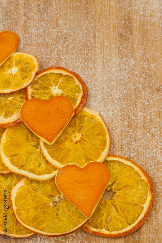 slices of dried orange peel and hearts of on a wooden background