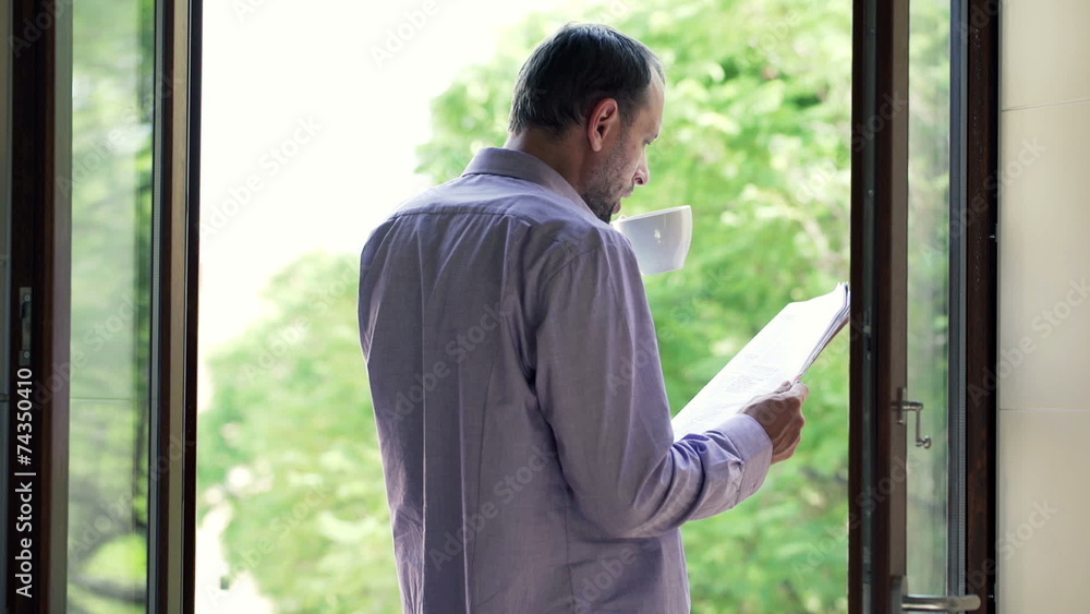 Man drinking coffee and reading newspaper by the window Man drinking coffee and reading newspaper by the window