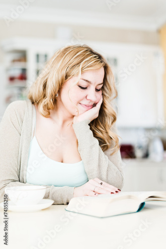 Beautiful woman reads an interesting book and drinks coffee