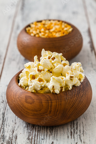 Popcorn and Ripe Corn in Wooden Bowls on White Wooden Table