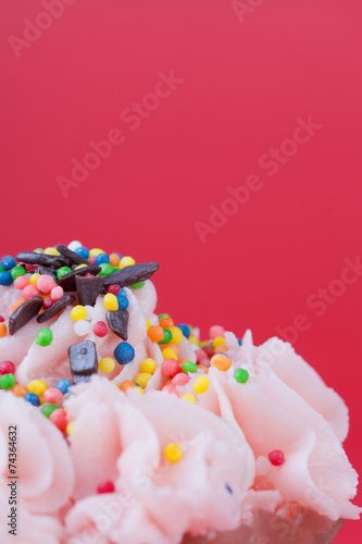 Cupcake with pink cream on a red background close up