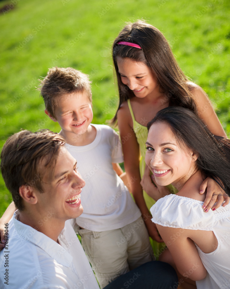 Junge glückliche Familie sitzt im Sommer im Gras Junge glückliche Familie sitzt im Sommer im Gras
