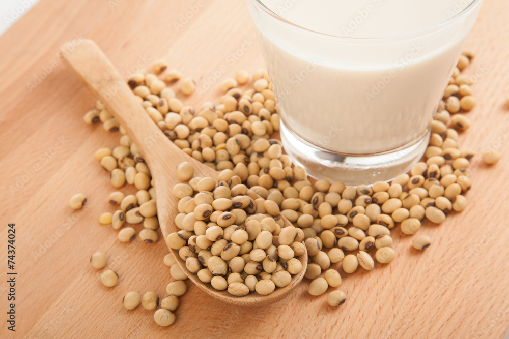 Soy milk in glass with soybeans and wooden spoon Soy milk in glass with soybeans and wooden spoon