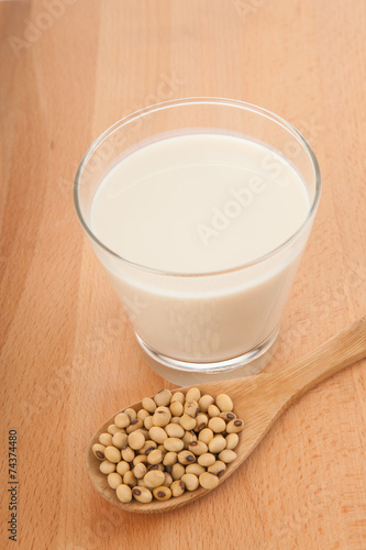 Soy milk in glass with soybeans and wooden spoon