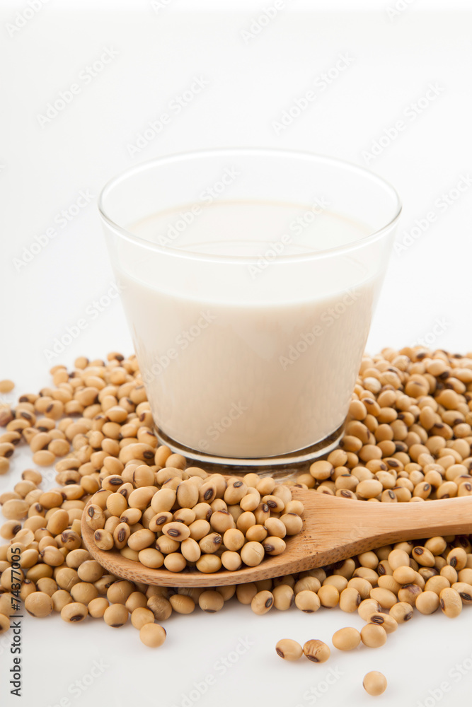 Soy milk in glass with soybeans and wooden spoon Soy milk in glass with soybeans and wooden spoon