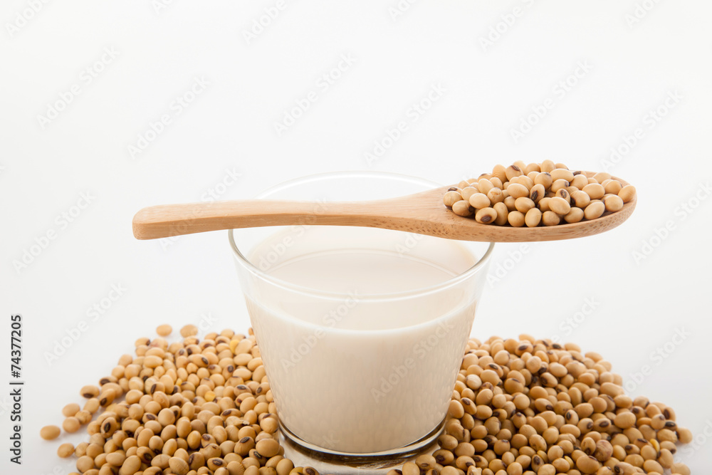 Soy milk in glass with soybeans and wooden spoon Soy milk in glass with soybeans and wooden spoon