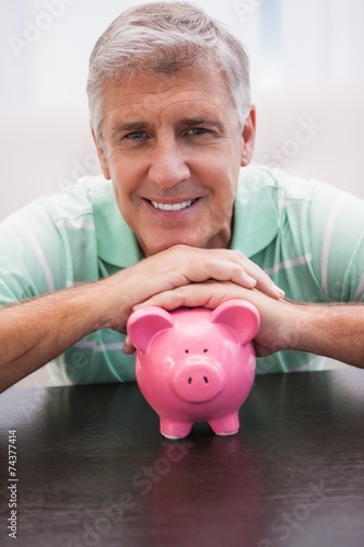 Smiling mature man with piggy bank
