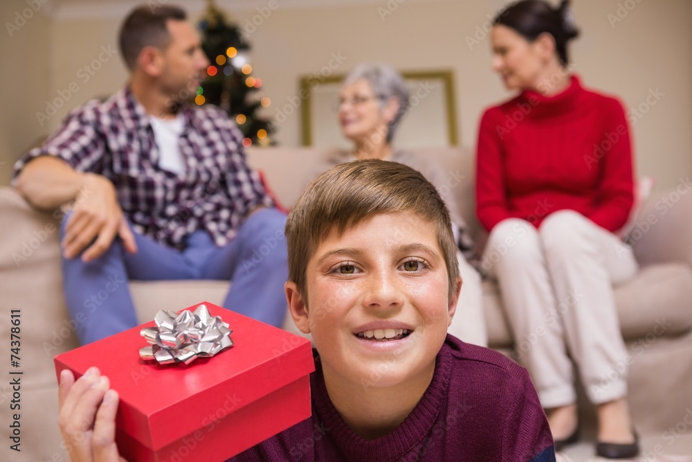 Smiling son with gift in front of his family Smiling son with gift in front of his family