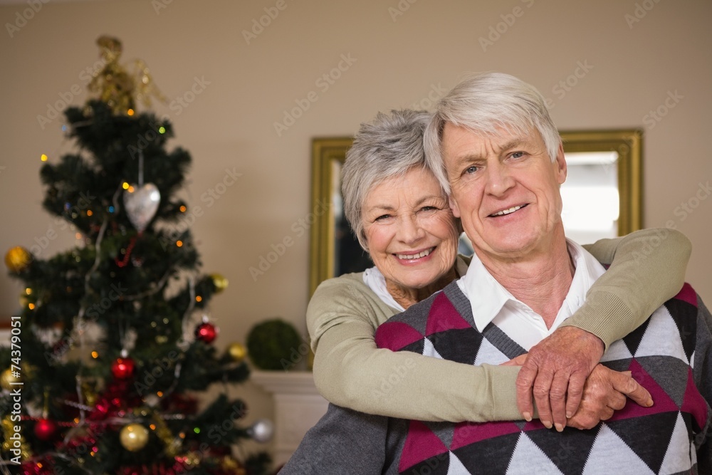 Senior couple smiling beside their christmas tree Senior couple smiling beside their christmas tree