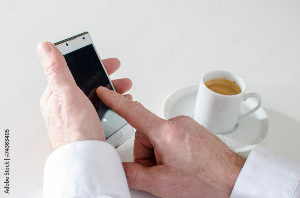 Man texting with smartphone and drinking a coffee Man texting with smartphone and drinking a coffee