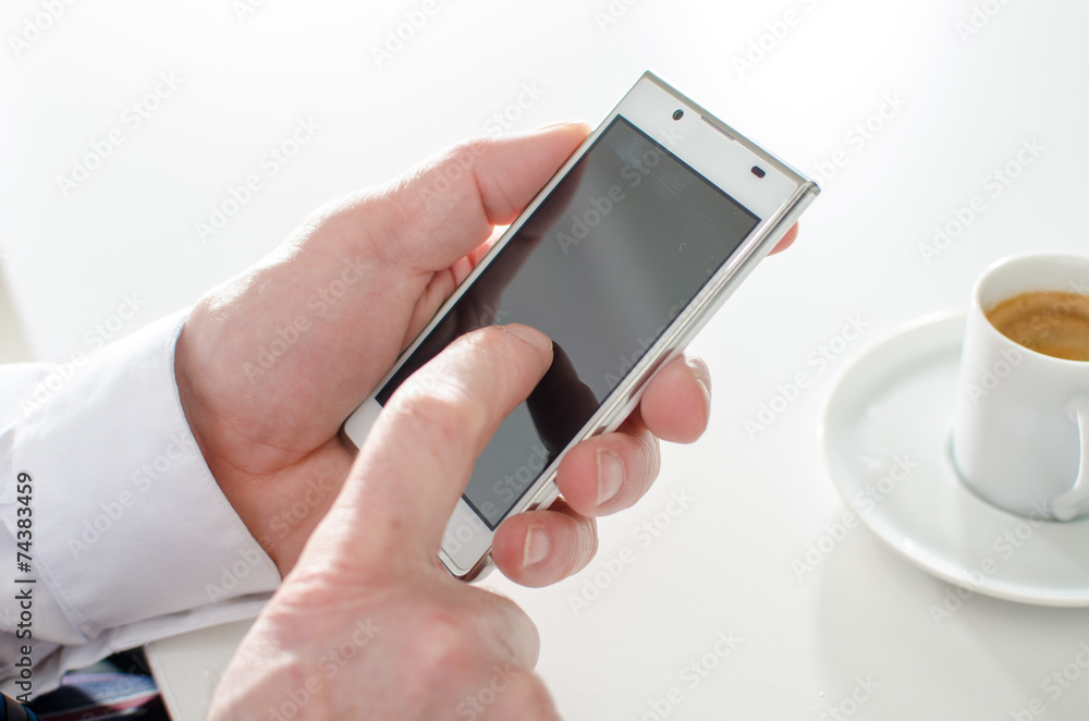 Businessman texting with smartphone and drinking a coffee Businessman texting with smartphone and drinking a coffee