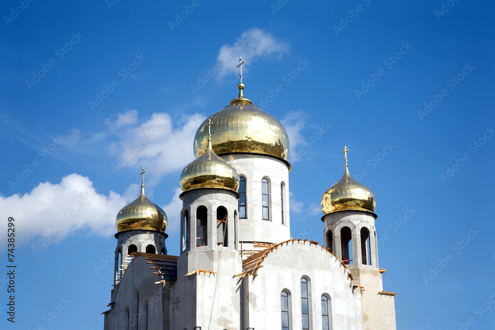 Construction of a new temple with gold domes against blue sky