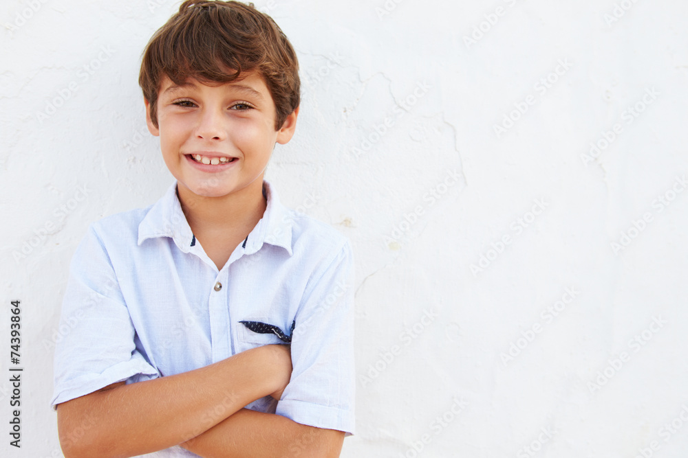 Smiling Young Boy Standing Outdoors Against White Wall Smiling Young Boy Standing Outdoors Against White Wall