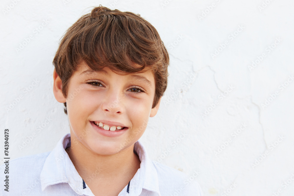 Smiling Young Boy Standing Outdoors Against White Wall Smiling Young Boy Standing Outdoors Against White Wall