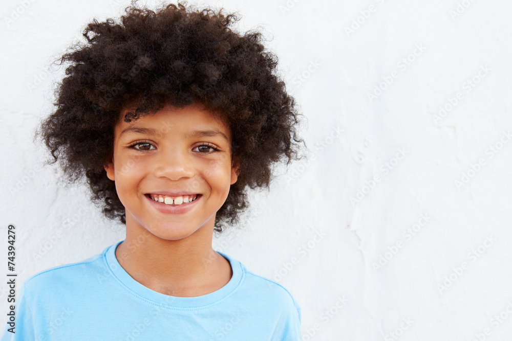 Smiling Young Boy Standing Outdoors Against White Wall Smiling Young Boy Standing Outdoors Against White Wall