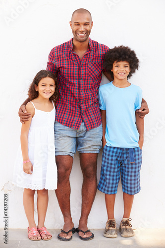 Father And Children Standing Outdoors Against White Wall