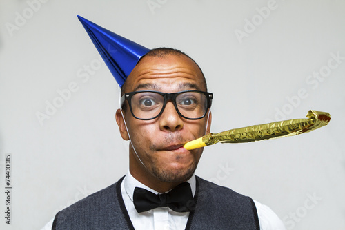 Young geek celebrating with party blower and hat