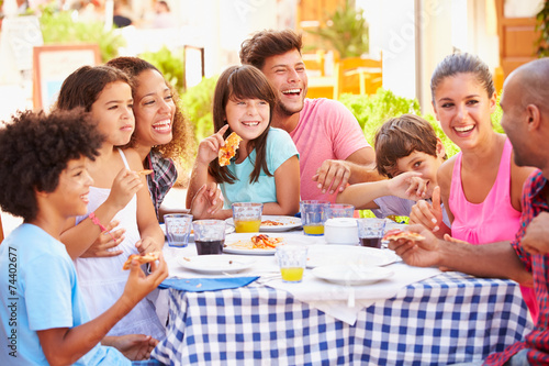 Two Families Eating Meal At Outdoor Restaurant Together