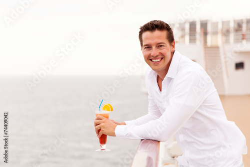 young man relaxing on cruise deck with cocktail