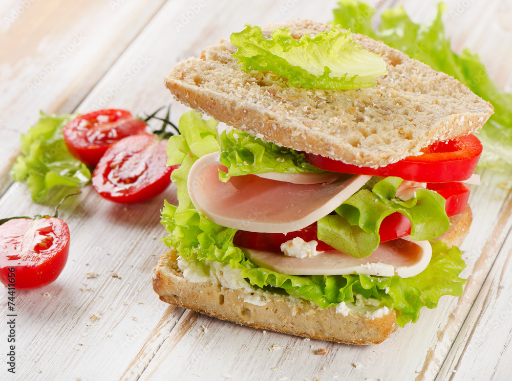 Sandwich with turkey and fresh vegetables on a wooden table Sandwich with turkey and fresh vegetables on a wooden table