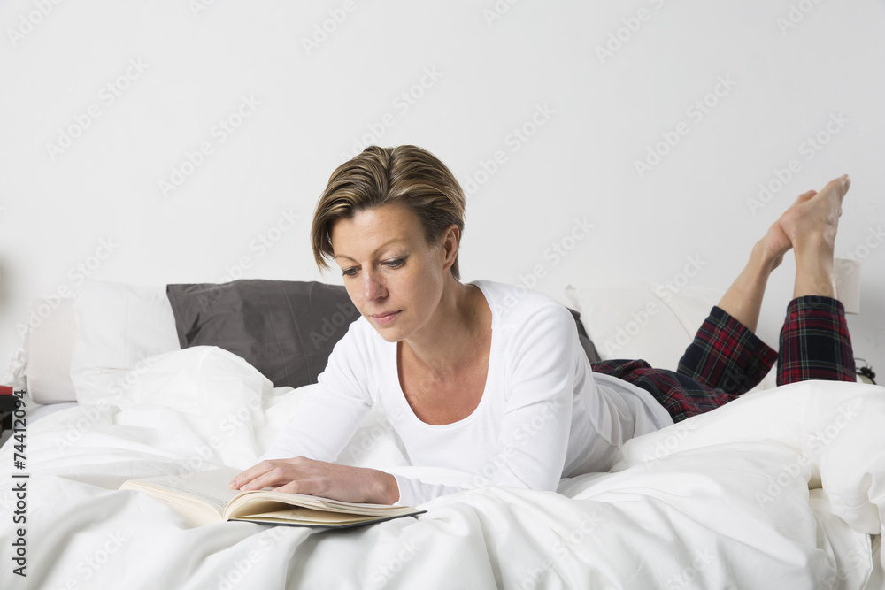 Woman reading a book in bed Woman reading a book in bed