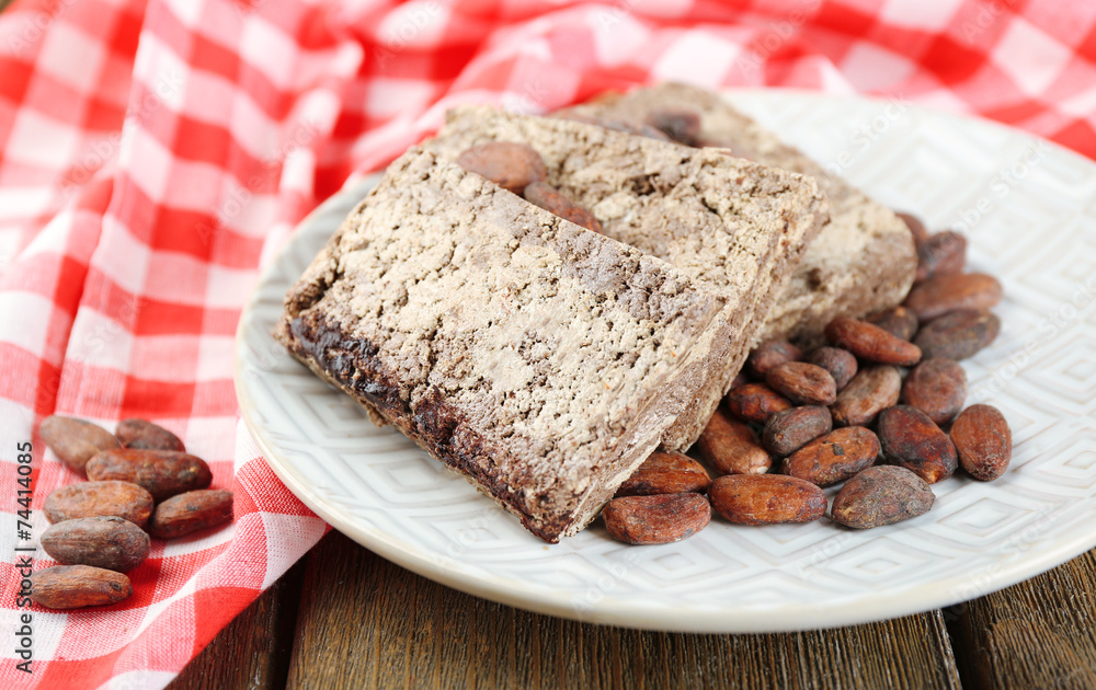 Fototapeta premium Sunflower halva with cocoa on plate, on wooden background