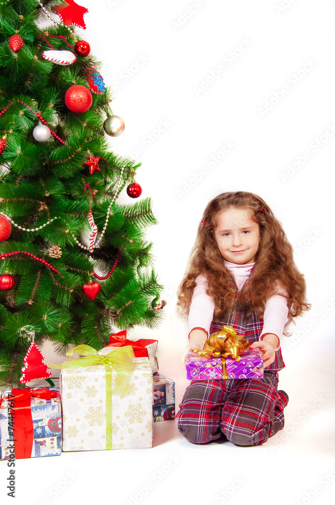 Little girl near the Christmas tree with gifts and toys