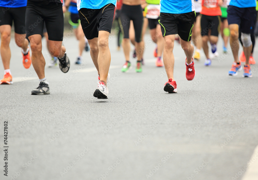 Unidentified marathon athletes legs running on city road Unidentified marathon athletes legs running on city road