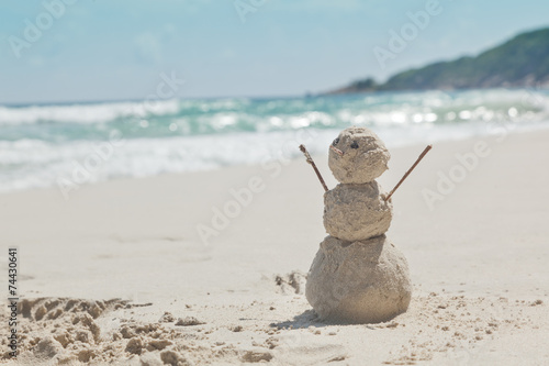 snowman made of sand on a background of the tropical warm sea