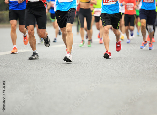Unidentified marathon athletes legs running on city road 