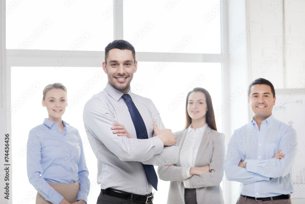 smiling businessman in office with team on back smiling businessman in office with team on back