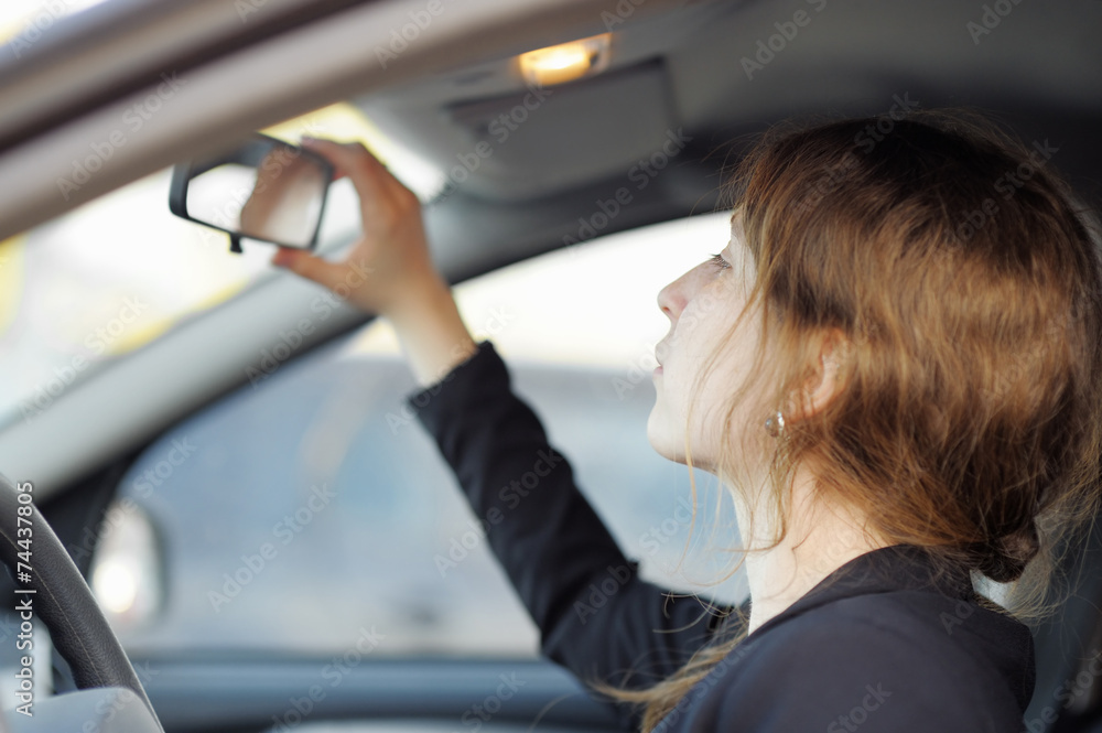 Woman looking in the mirror in a car