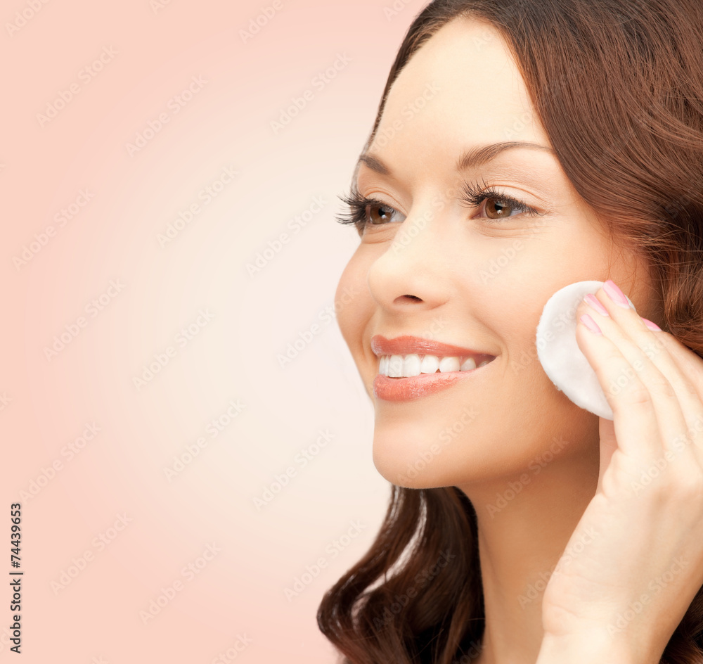 smiling woman cleaning face skin with cotton pad
