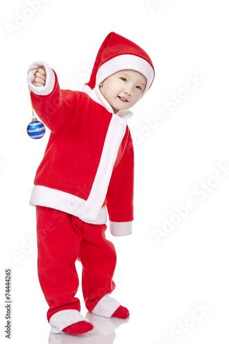 Sweet baby wearing a Santa costume, smiling and holding a small