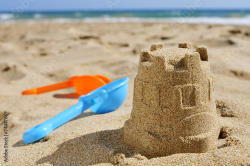 sandcastle and toy shovels on the sand of a beach photo