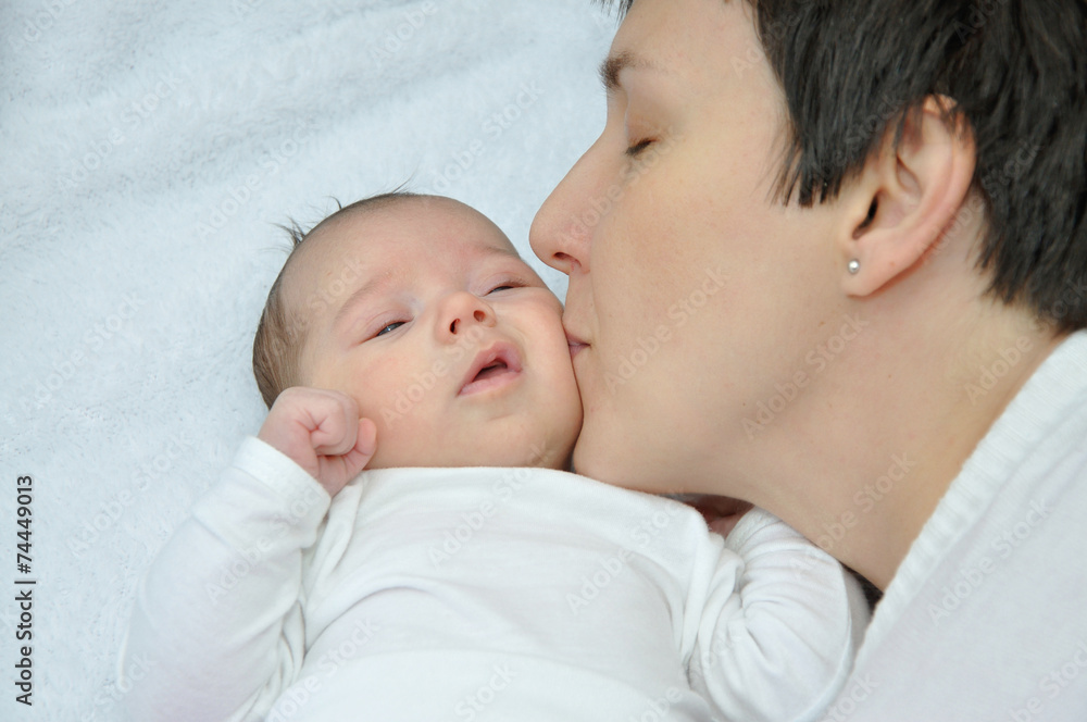 Happy mother kissing her lovely newborn baby girl Happy mother kissing her lovely newborn baby girl