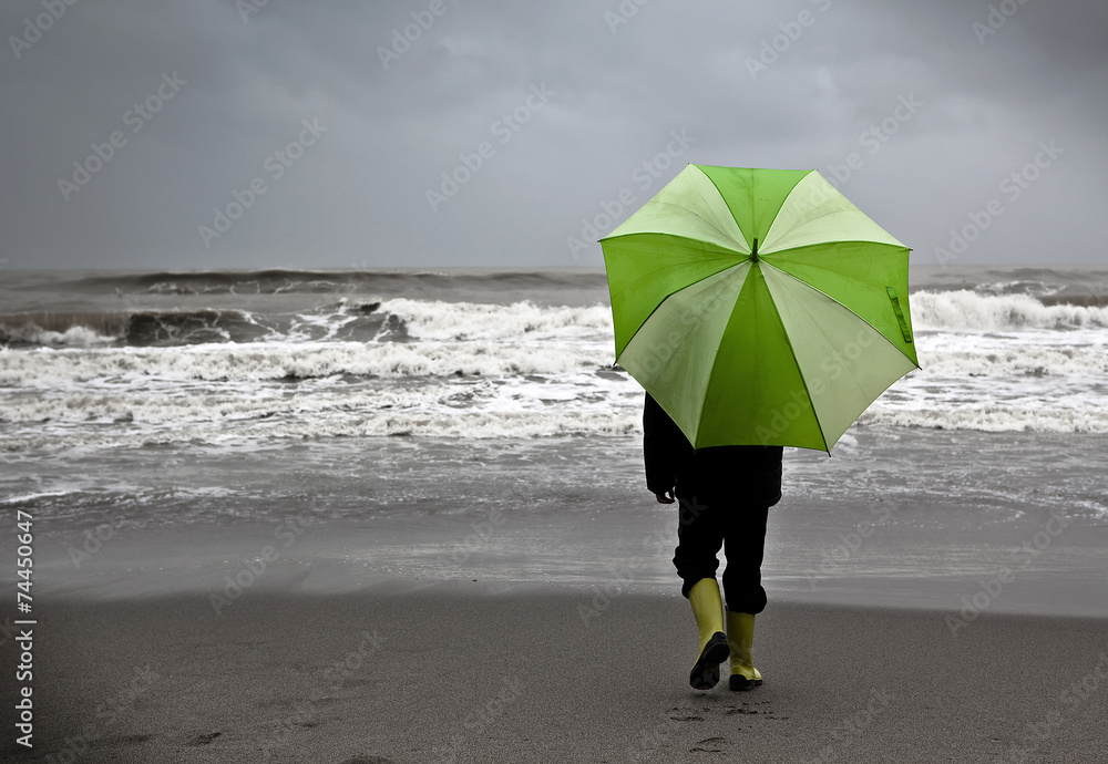 Niño bajo la lluvia en la playa con paraguas foto de Stock | Adobe Stock