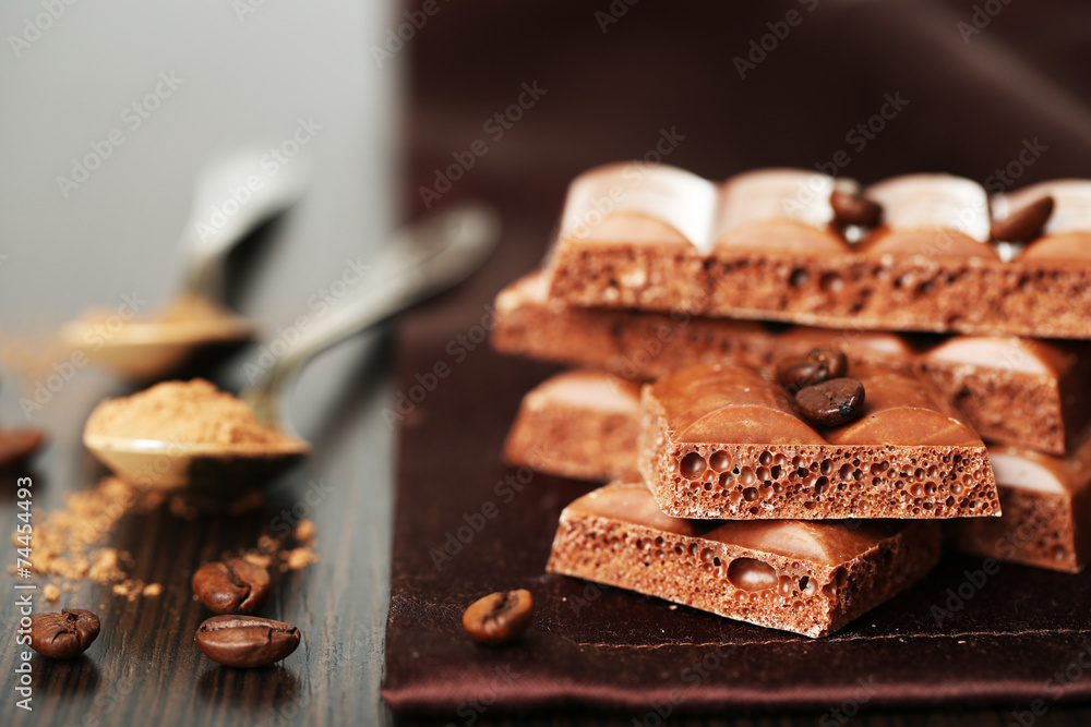 Tasty porous chocolate with coffee beans on table, close up Tasty porous chocolate with coffee beans on table, close up