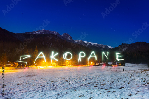 Zakopane sign under Tatra mountains at night, Poland