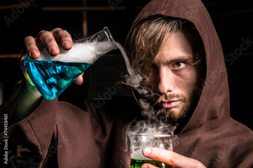 Alchemist in chemical laboratory prepares magical liquids photo